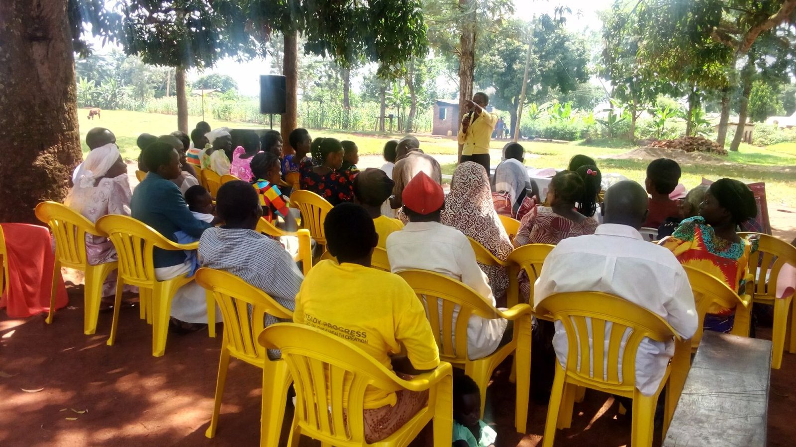 A facilitator speaking to a seated community group outdoors